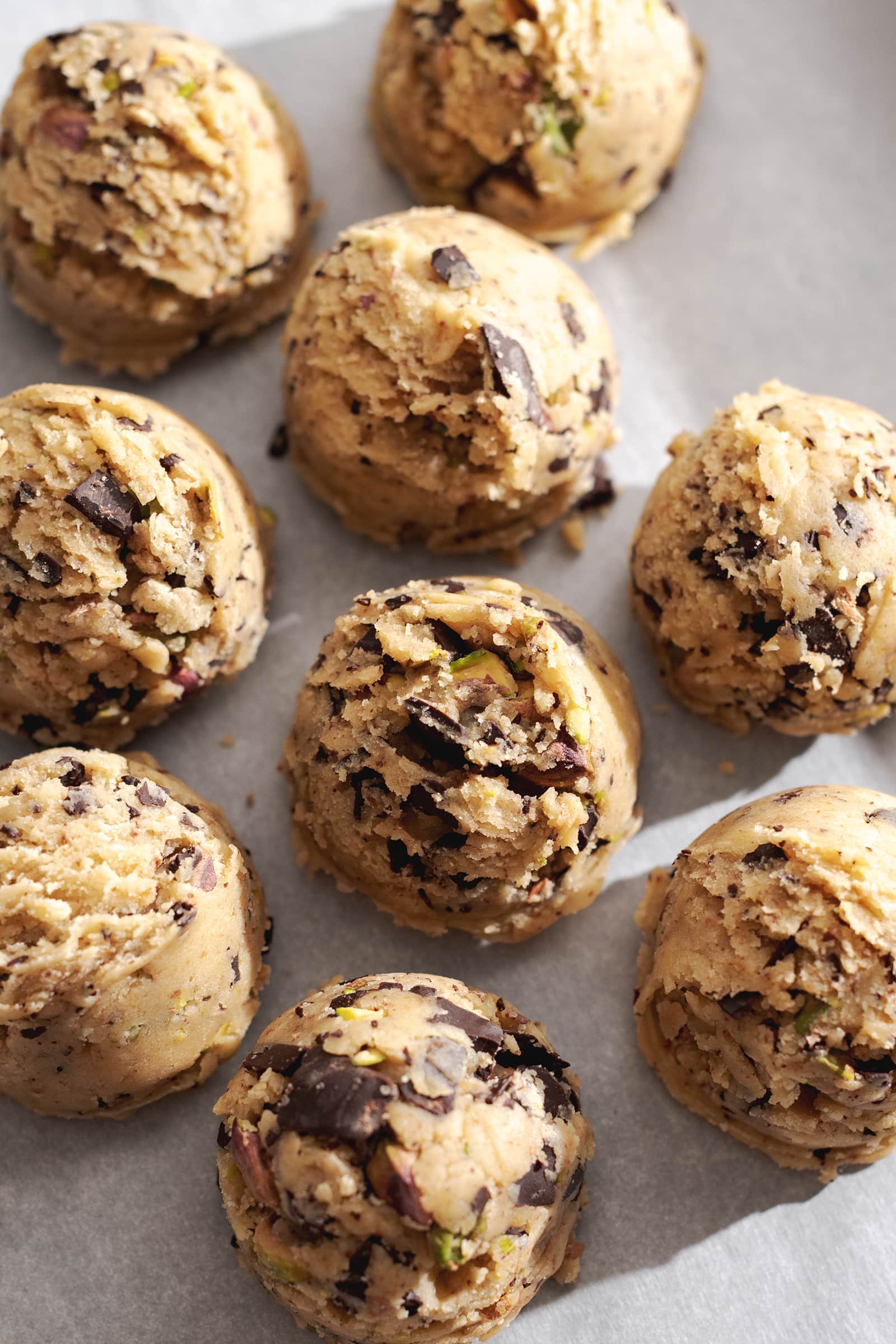 Balls of cookie dough lined up on parchment paper.