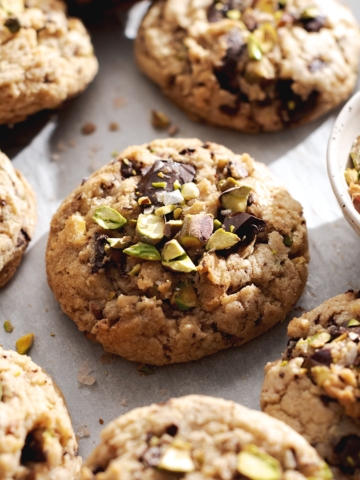 Pistachio chocolate chip cookie surrounded by many other cookies.