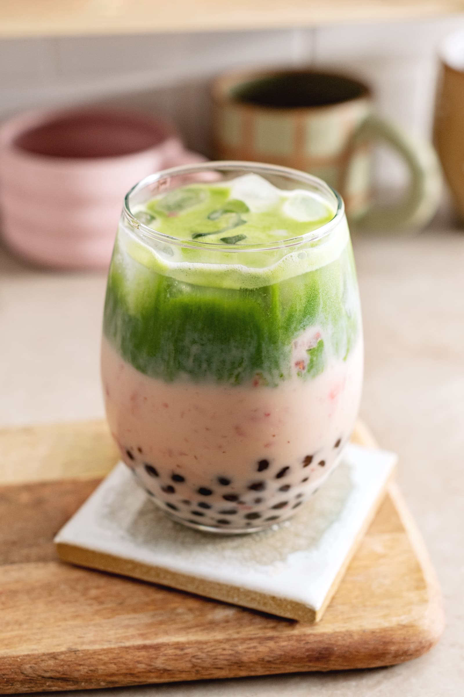Glass filled with boba pearls, strawberry milk, and matcha split into two layers.