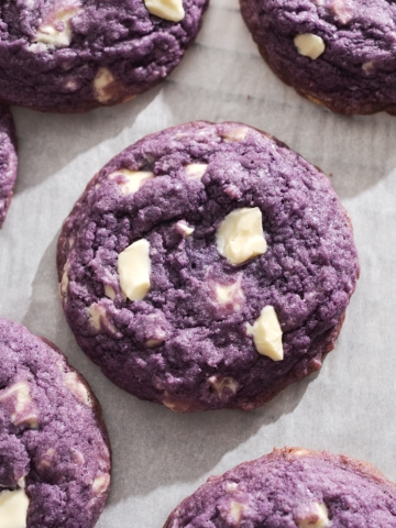 Ube cookie with white chocolate chunks on parchment paper.