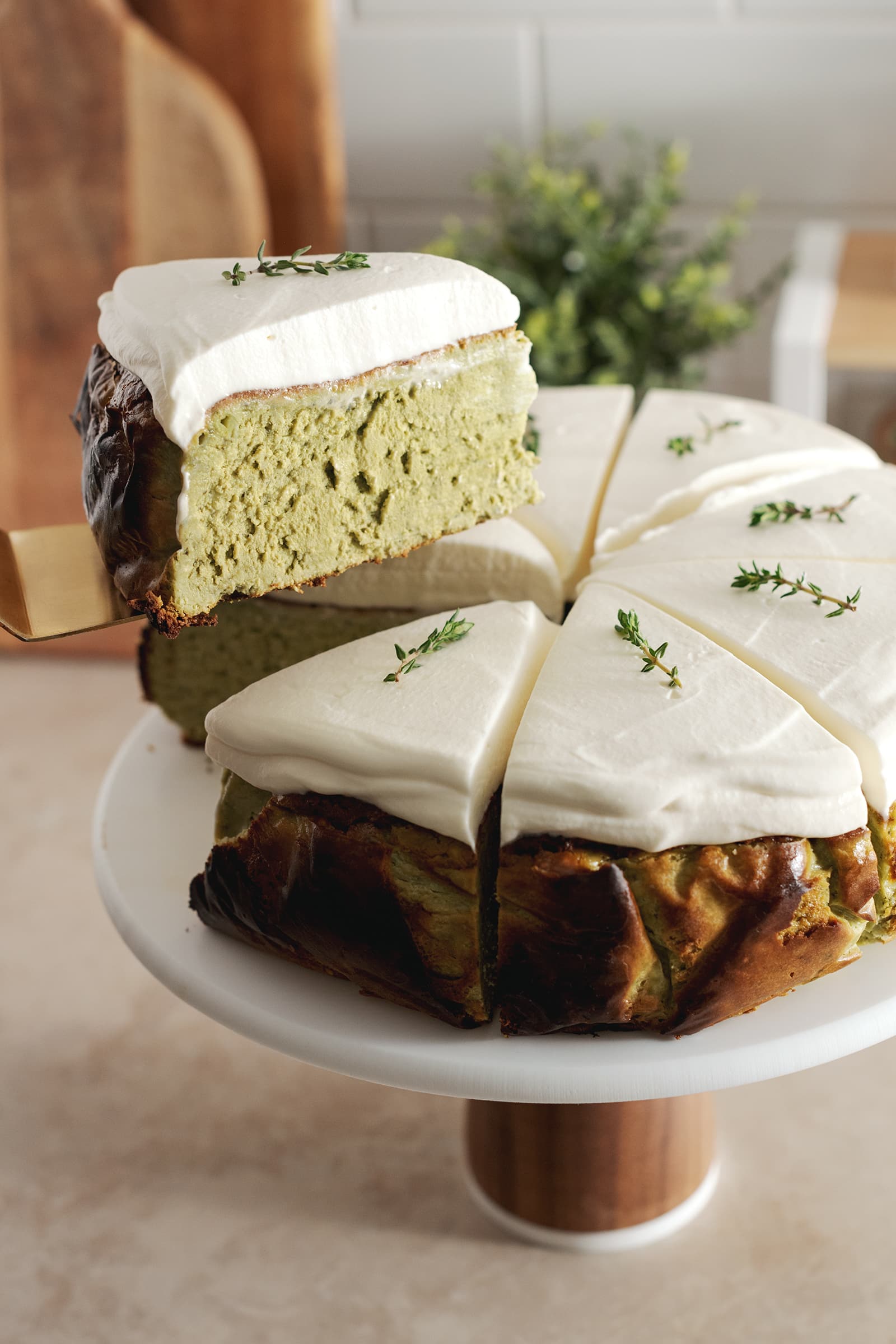 Lifting a slice of matcha basque cheesecake from the rest of the cake.