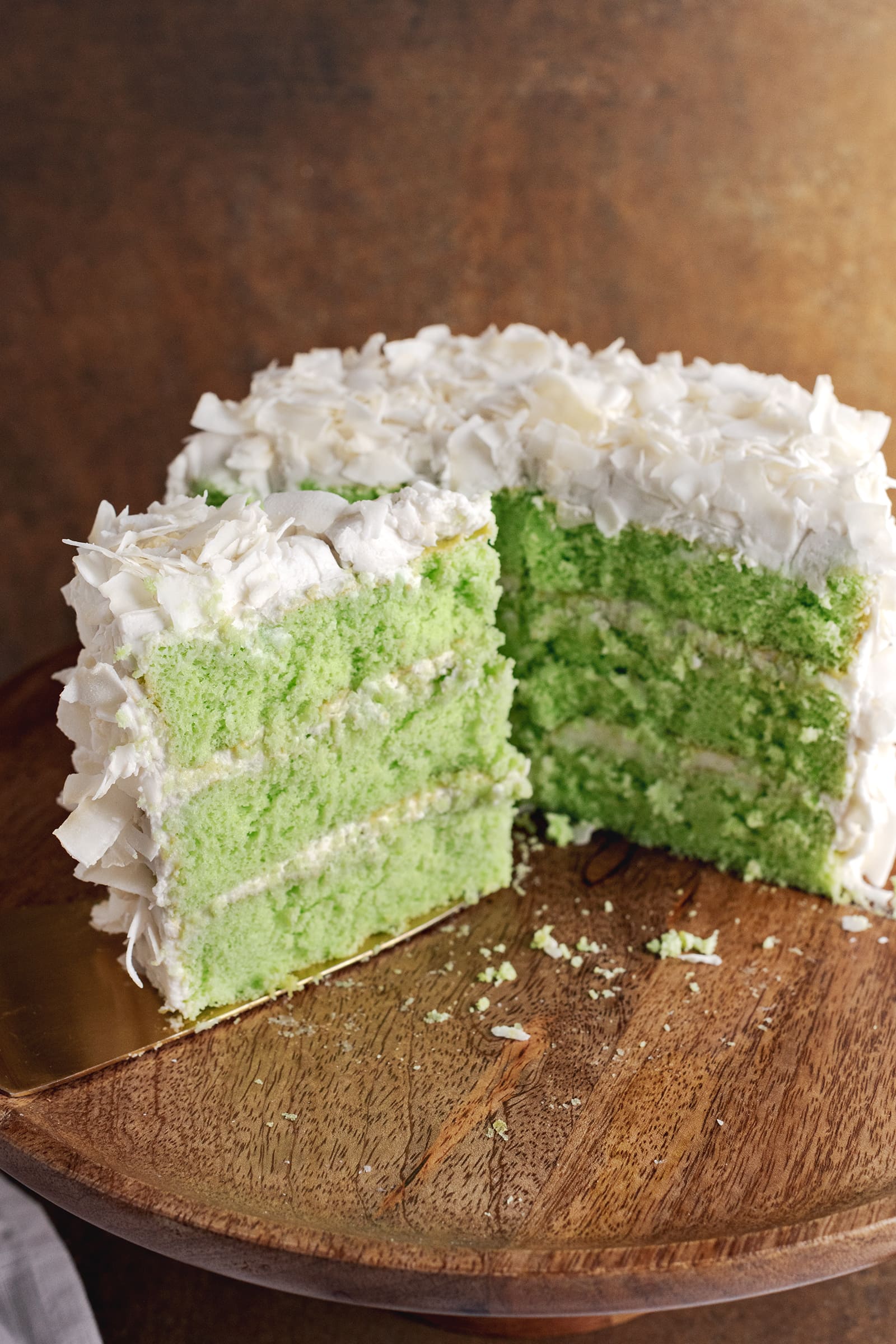 A slice of pandan coconut cake in front of half of a cake in the background.