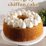 A chiffon cake topped with dollops of whipped cream on a cake stand.