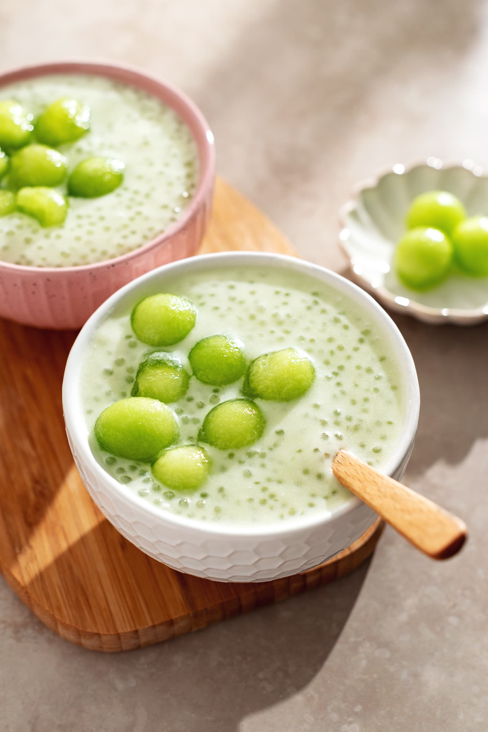 Two bowls of honeydew sago pudding with honeydew melon balls on top.