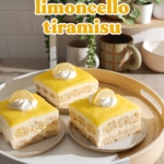 Three slices of limoncello tiramisu on a round platter in front of a shelf with plants and mugs.