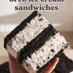 Hand holding a stack of two oreo ice cream sandwiches to show the layers.