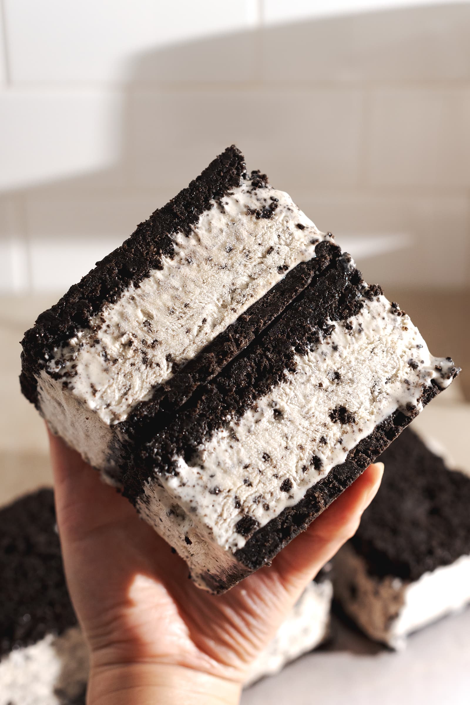 Hand holding a stack of two oreo ice cream sandwiches to show the layers.