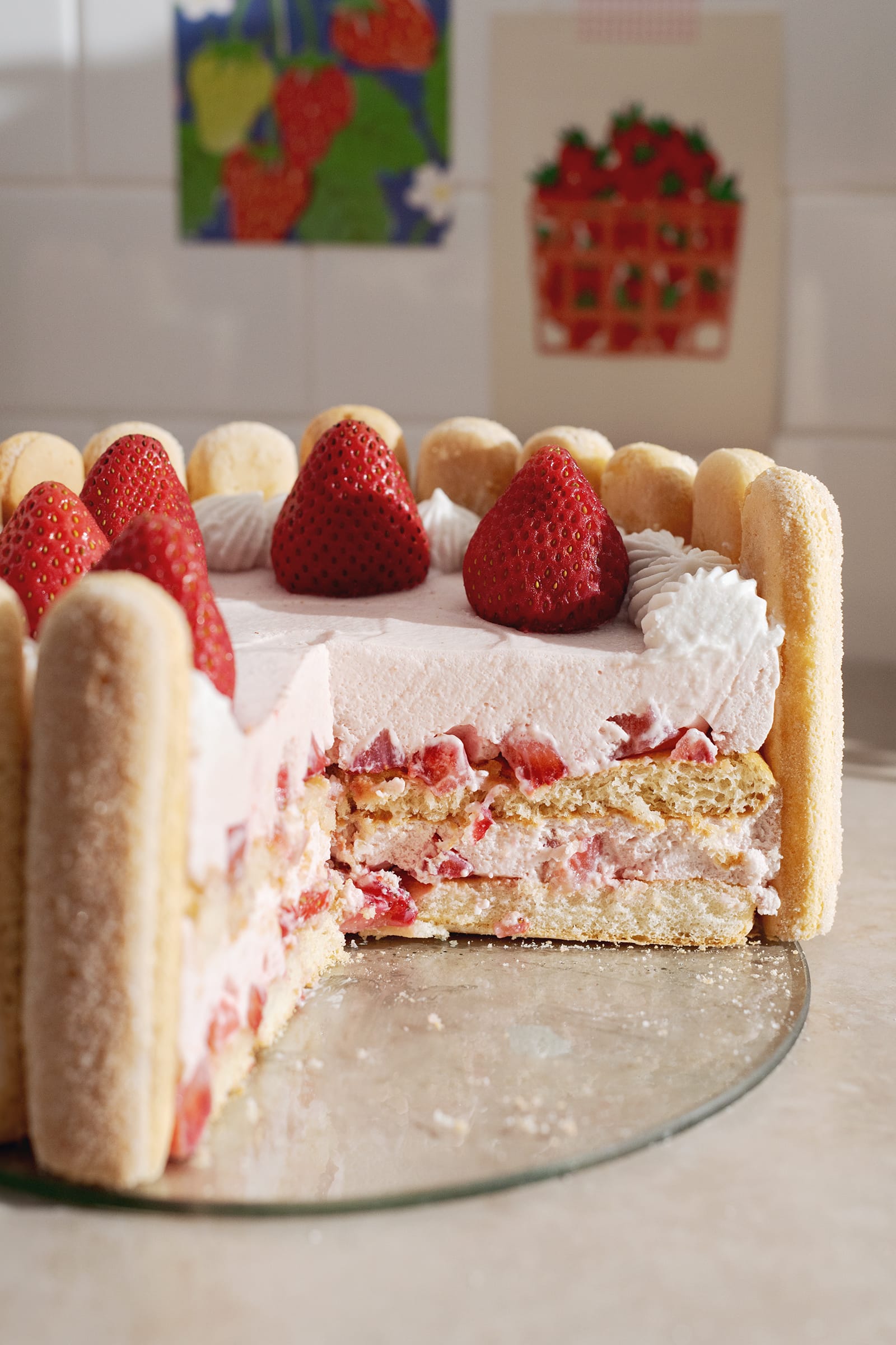 Cross section of a charlotte cake showing the layers of ladyfingers, strawberry mousse, and strawberries inside.