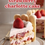 A slice of strawberry charlotte cake on a plate showing the layers and whole strawberry on top.