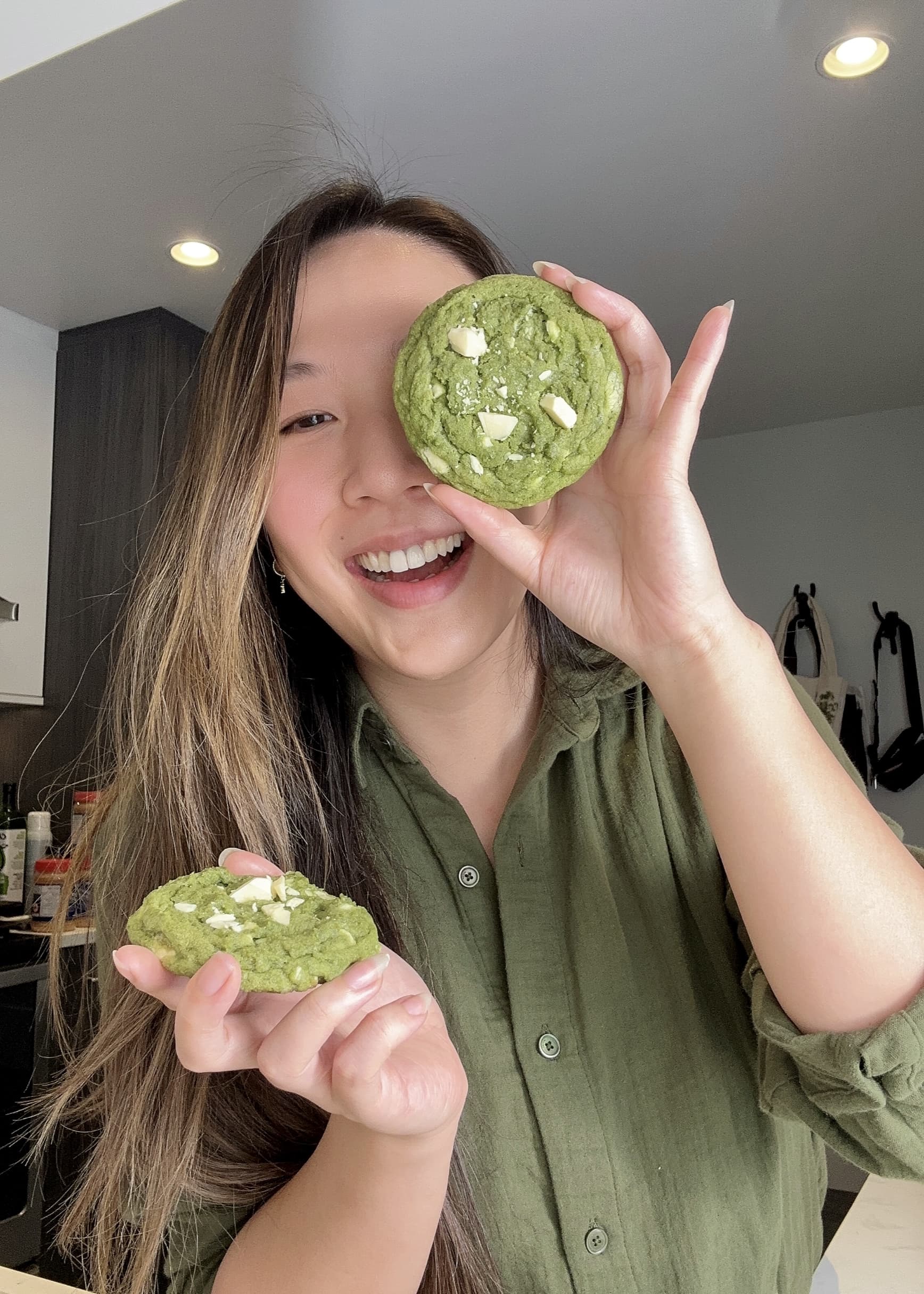 Girl holding matcha cookie up to cover eye.