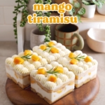 Individual containers of mango tiramisu on a kitchen counter with shelf in the back.