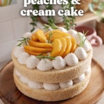 Two-layer peaches and cream cake on a wooden cake stand on kitchen counter.