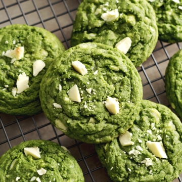 Matcha white chocolate cookies stacked on a wire rack.