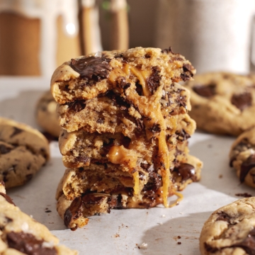 A stack of miso caramel cookies cut in half to show the goey caramel inside.