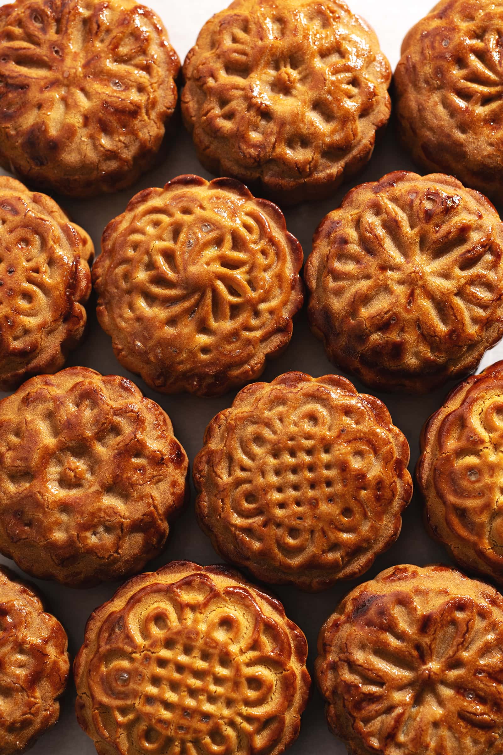 Several baked mooncakes with different designs lined up across the frame.