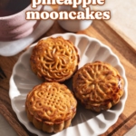Three mooncakes on a plate on a tray with a cup of tea.