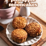 Three mooncakes on a plate on a tray with a cup of tea.