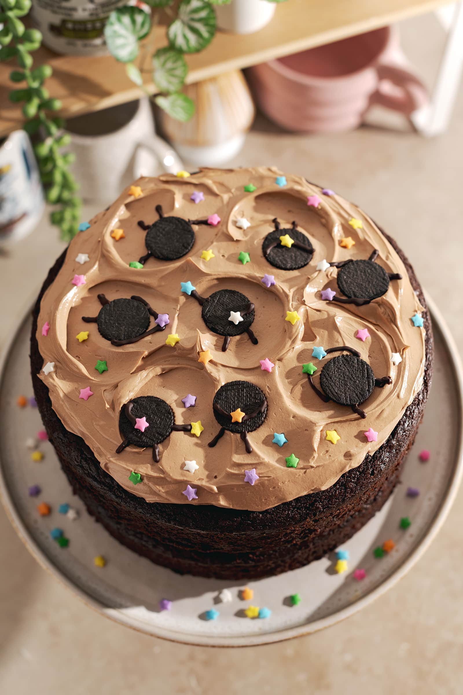 Mini oreo soot sprites and star sprinkles on top of chocolate buttercream on a chocolate cake.