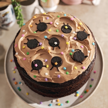 Mini oreo soot sprites and star sprinkles on top of chocolate buttercream on a chocolate cake.