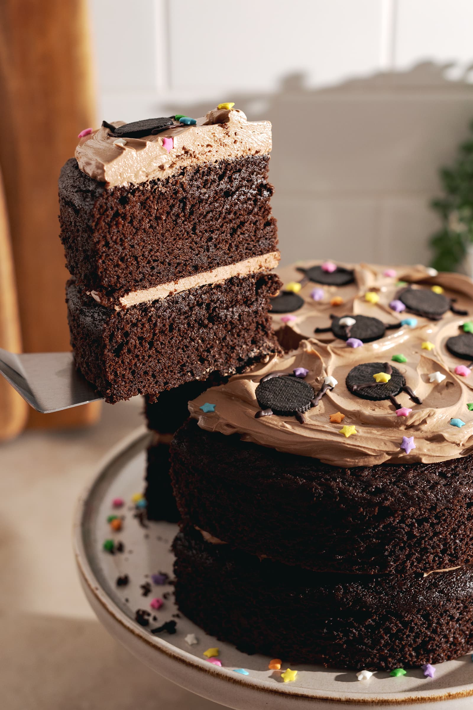 Lifting a slice of chocolate cake with a cake server from the rest of the cake.