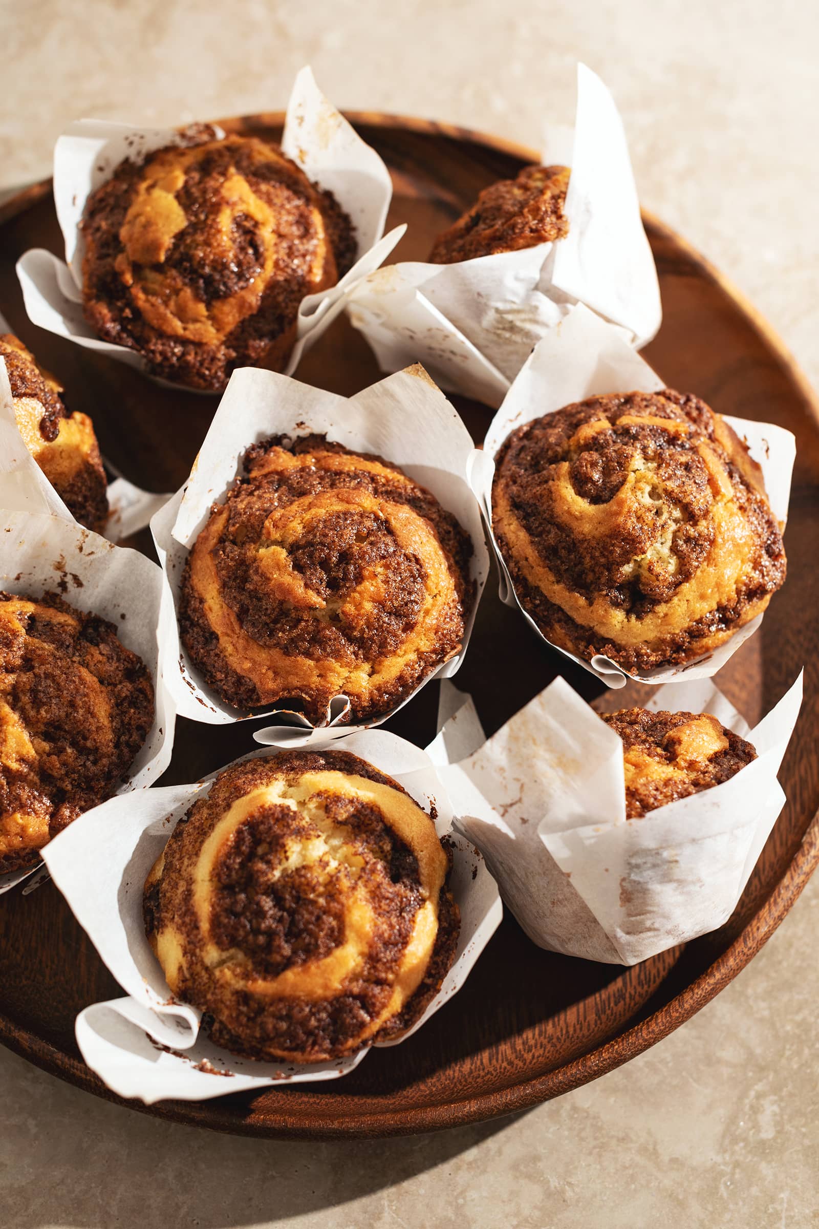 Several cinnamon roll muffins on a wooden platter.