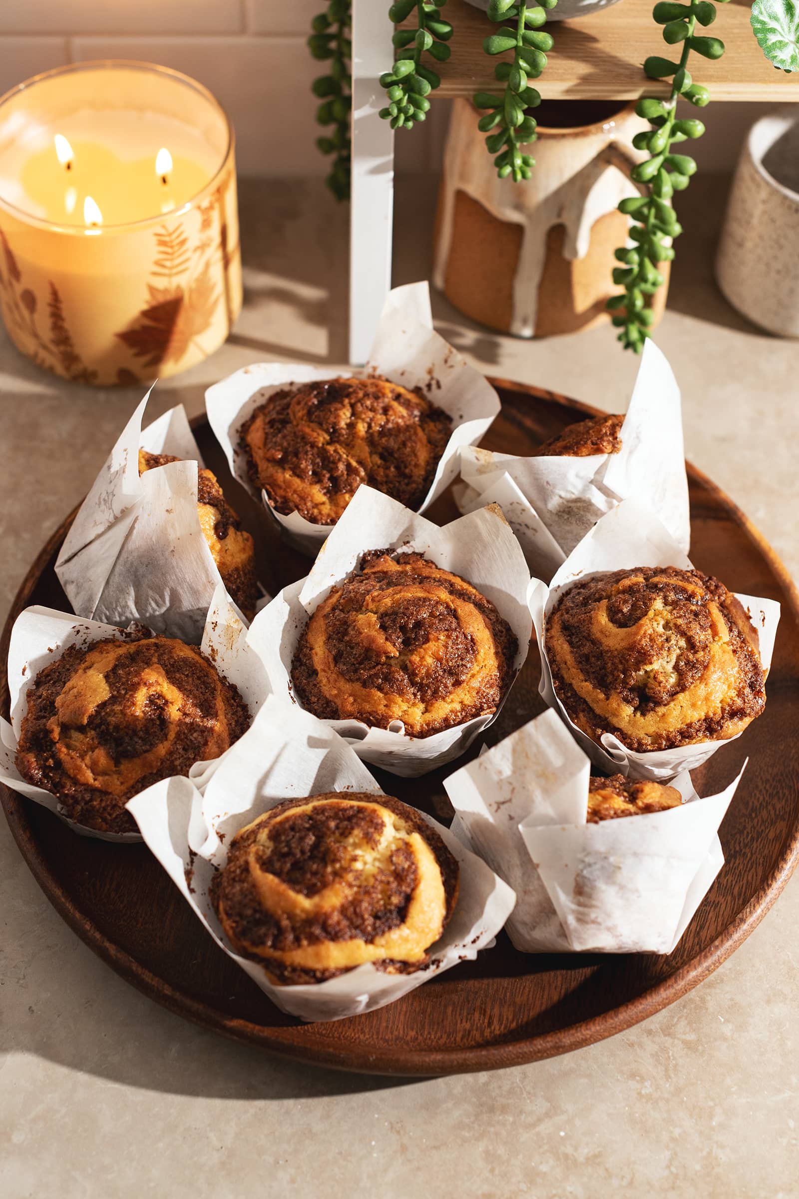 Cinnamon roll muffins in muffin liners on a wooden platter.