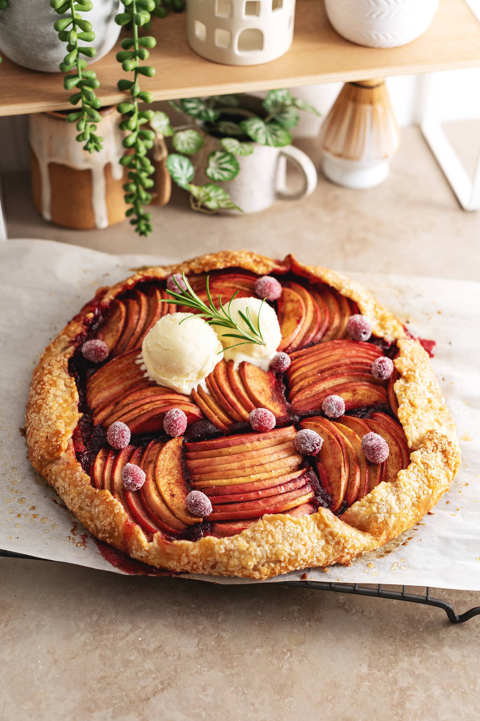 A cranberry apple galette sitting on a wire rack on a kitchen counter.