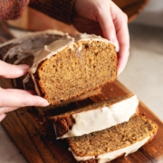 Hands holding a slice of earl grey pound cake above the rest of the loaf.
