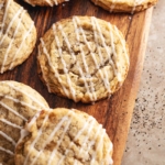 Earl grey sugar cookies drizzled with glaze scattered on a wooden board.
