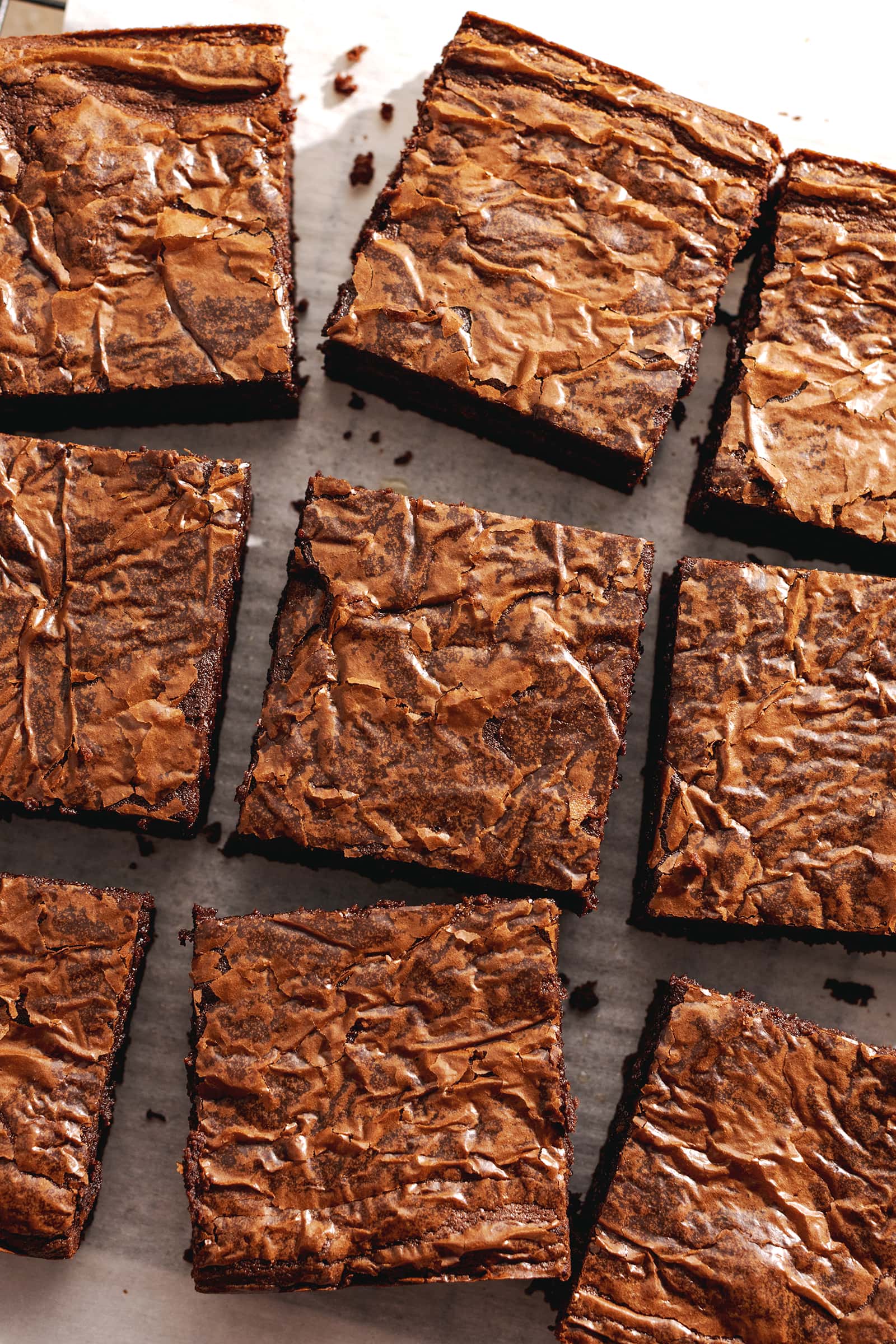Squares of miso brownies with crackly tops scattered on parchment paper.