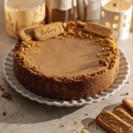 A whole biscoff cheesecake on a scalloped plate.