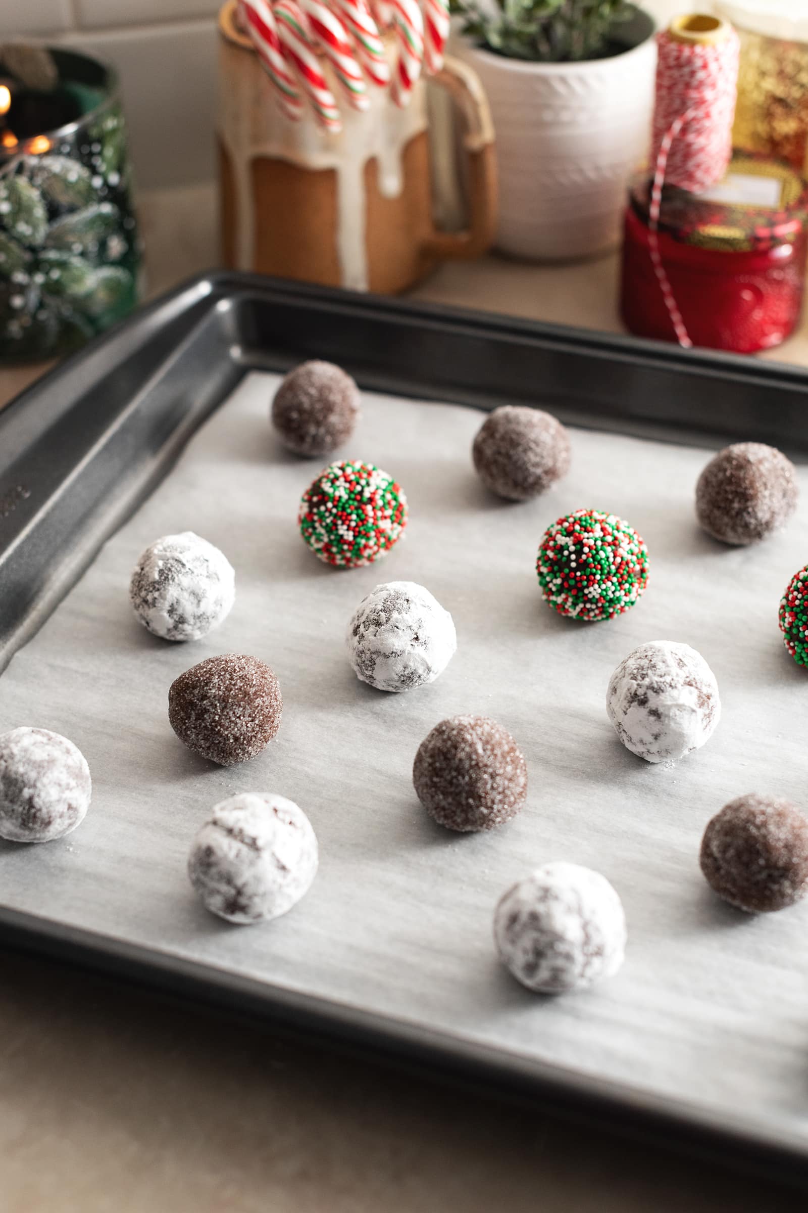 Balls of cookie dough coated in sugar and sprinkles arranged on a backing sheet.