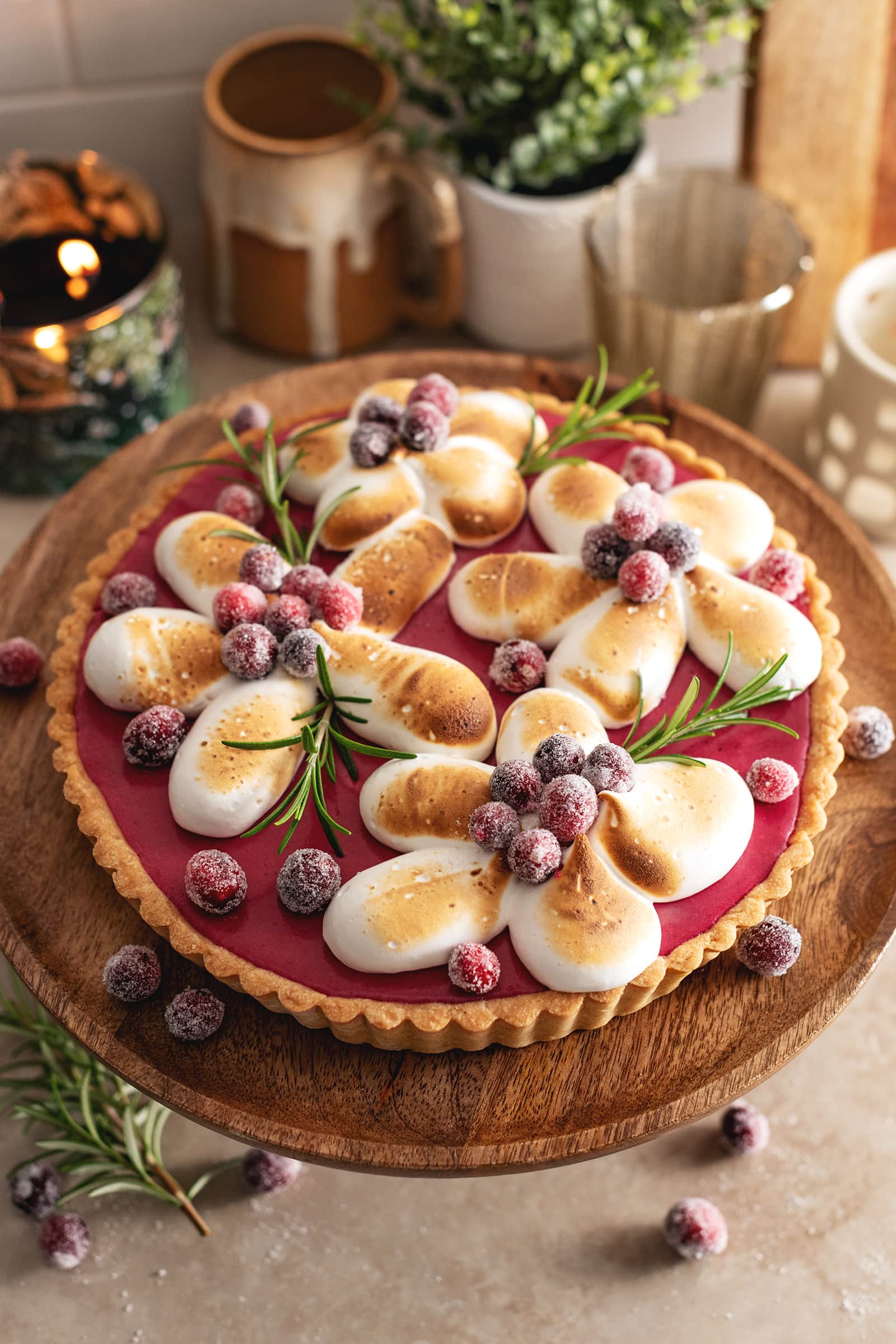 A cranberry meringue tart on a wooden cake stand.
