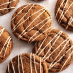 Gingerbread latte cookies drizzled with icing scattered on parchment paper.