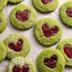 Matcha thumbprint cookies scattered on parchment paper.
