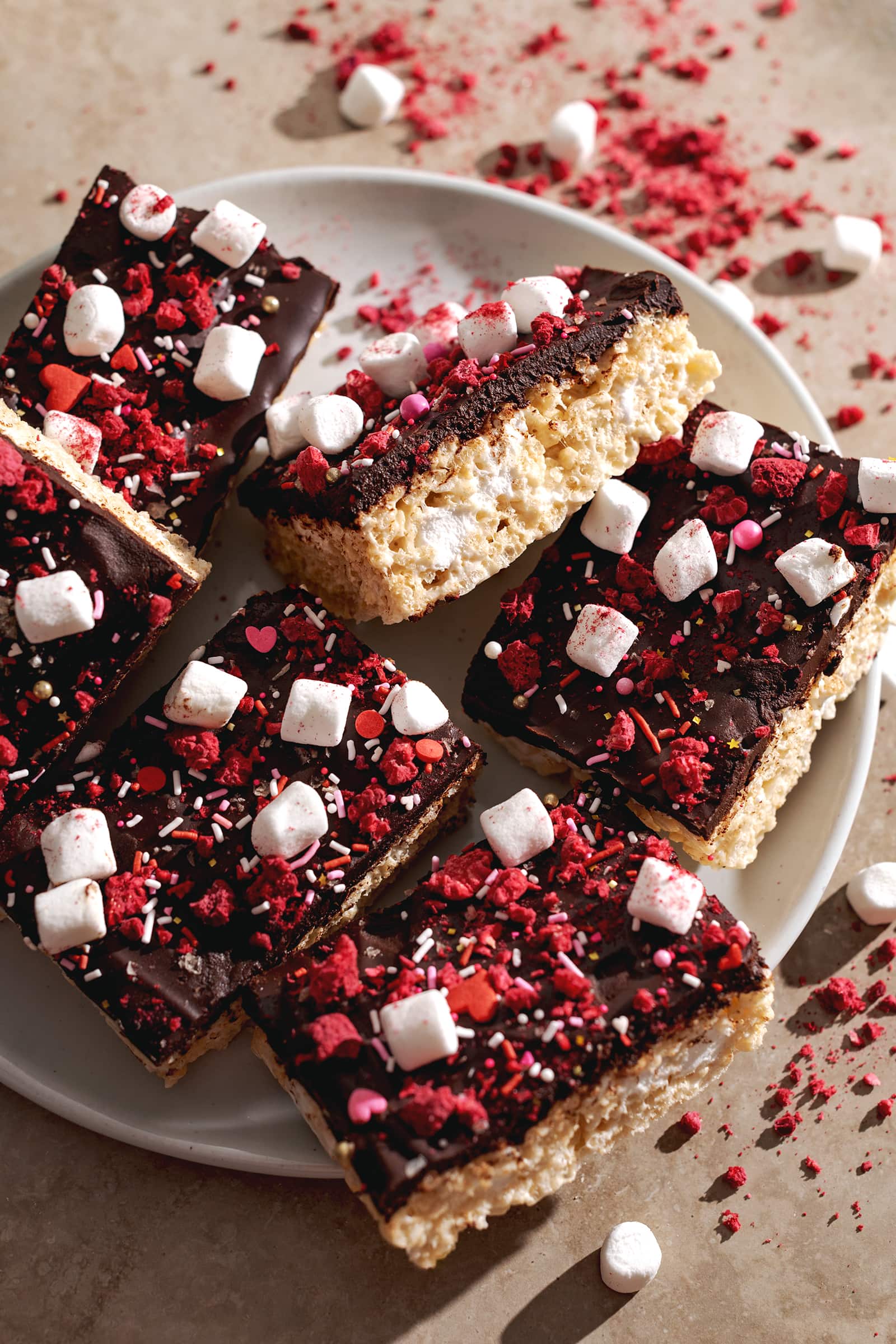 Rice krispie treats covered with chocolate and sprinkles on a plate.