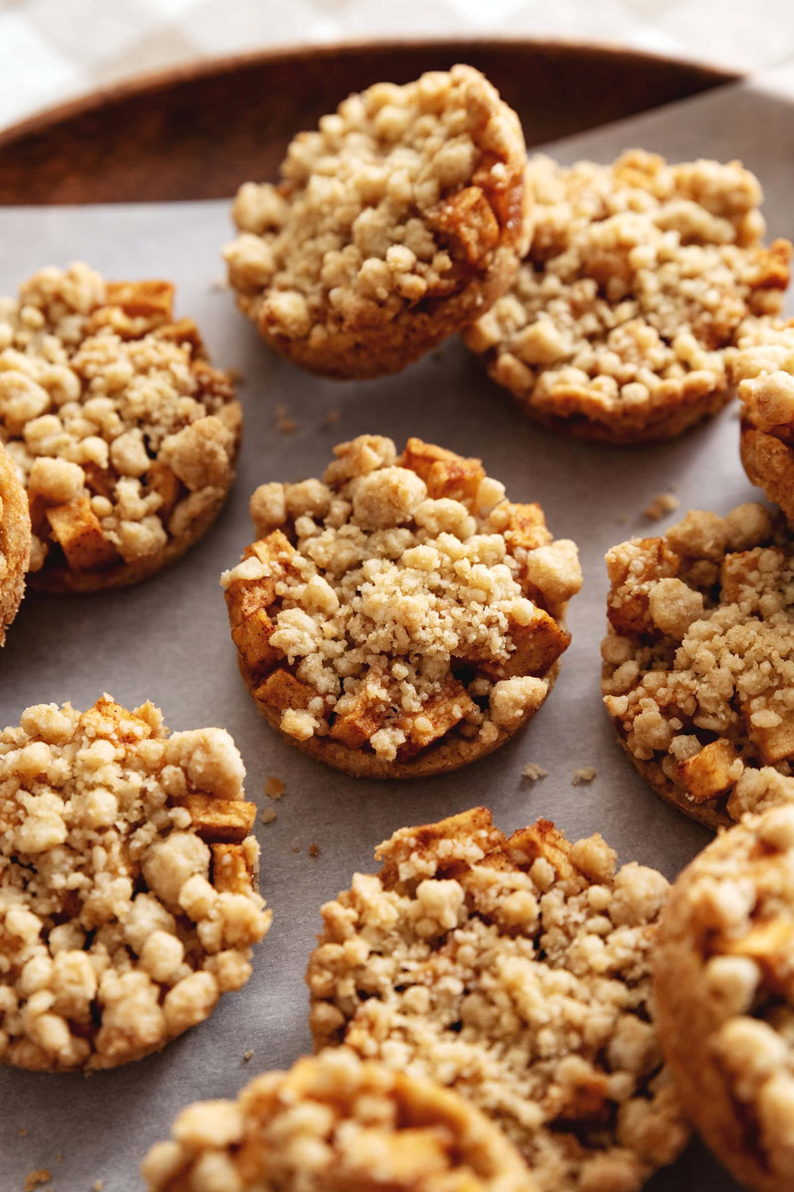 Close-up of apple crumble cookies scattered on a wooden tray.