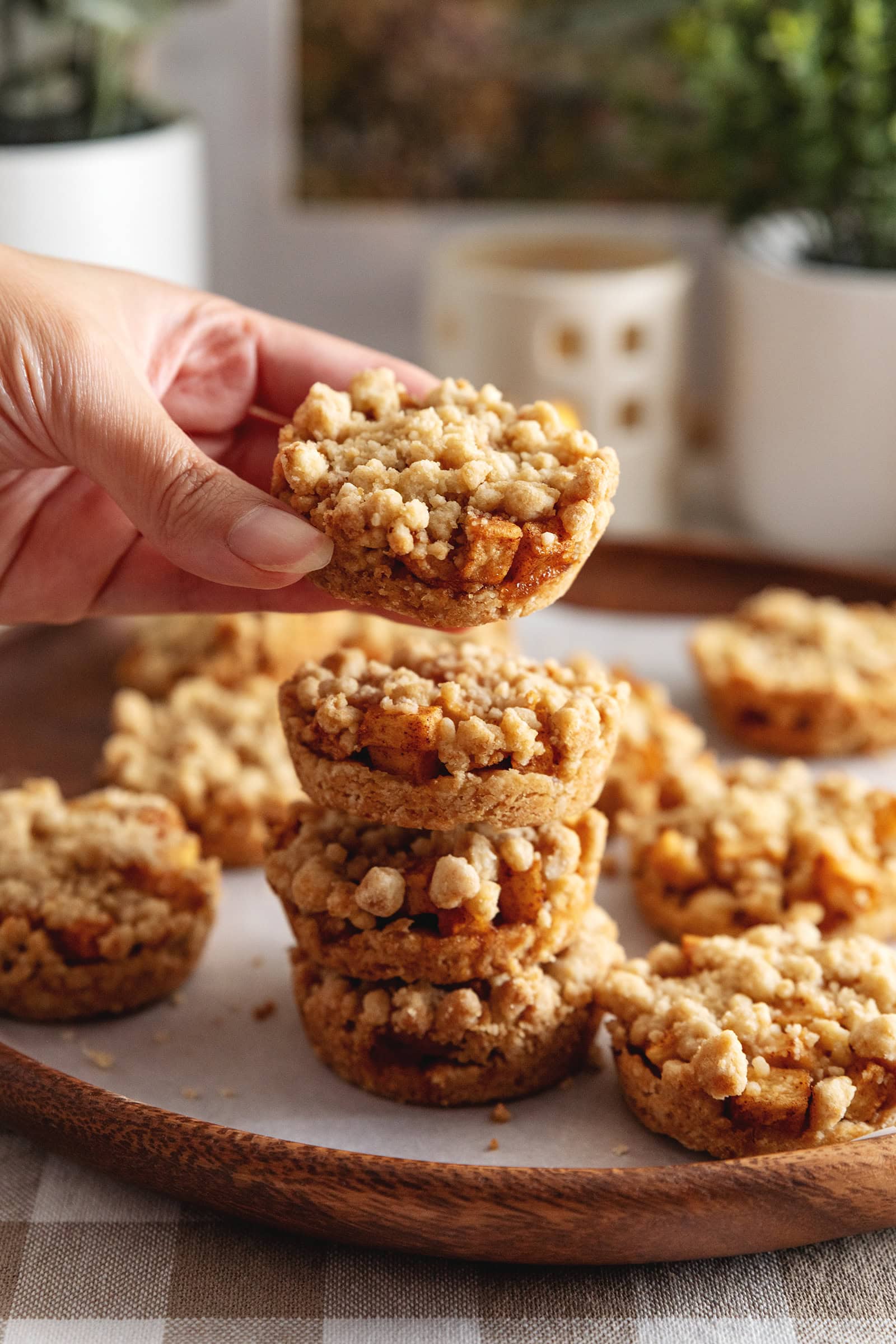 Hand holding an apple crumble cookie above a stack of cookies.