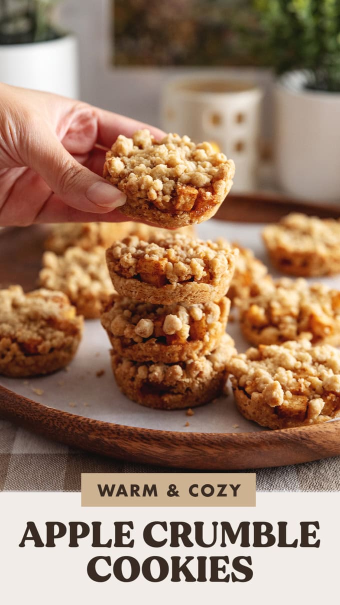 Hand holding an apple crumble cookie above a stack of cookies.