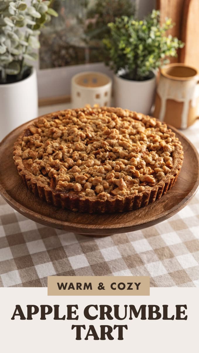 An apple crumble tart on a wooden cake stand.
