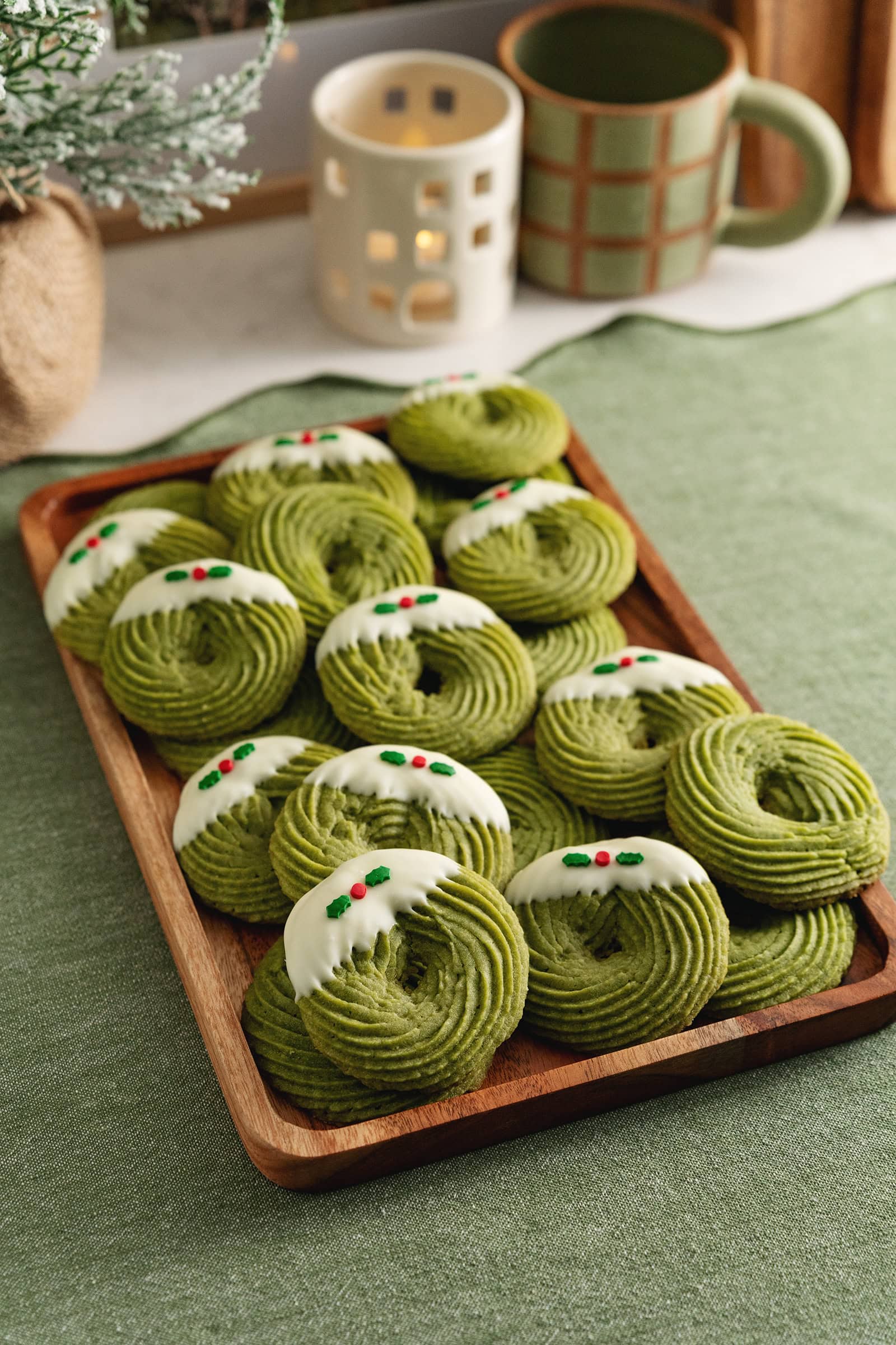 A tray of matcha butter cookies decorated with Christmas sprinkles on a kitchen counter.