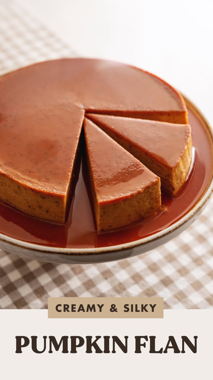 A pumpkin flan on a cake stand with two slices cut out of it.