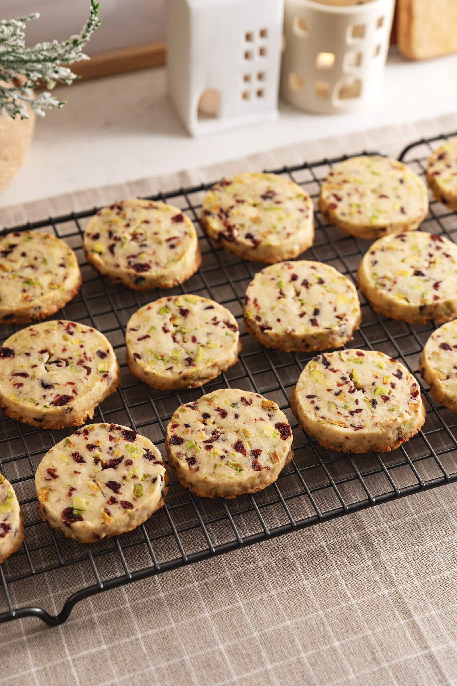 Cranberry pistachio shortbread cookies lined up in rows on a wire rack.