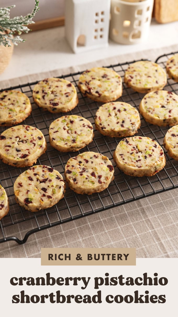 Cranberry pistachio shortbread cookies lined up in rows on a wire rack.