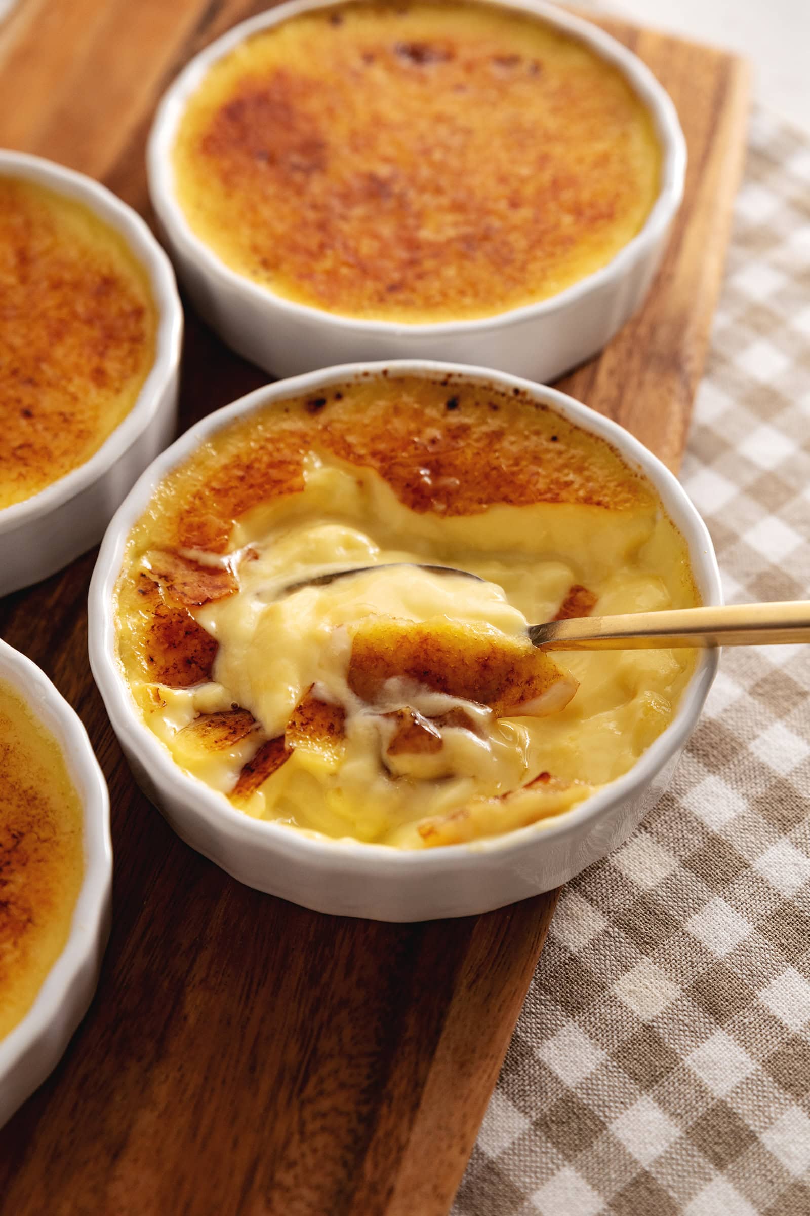 A ramekin of eggnog crème brûlée showing the custard underneath the caramelized sugar.