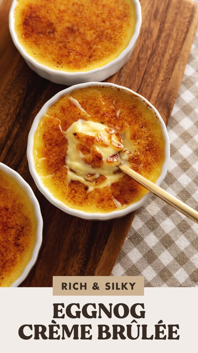 A ramekin of eggnog crème brûlée with a spoon resting in the custard under the crunchy sugar shards.
