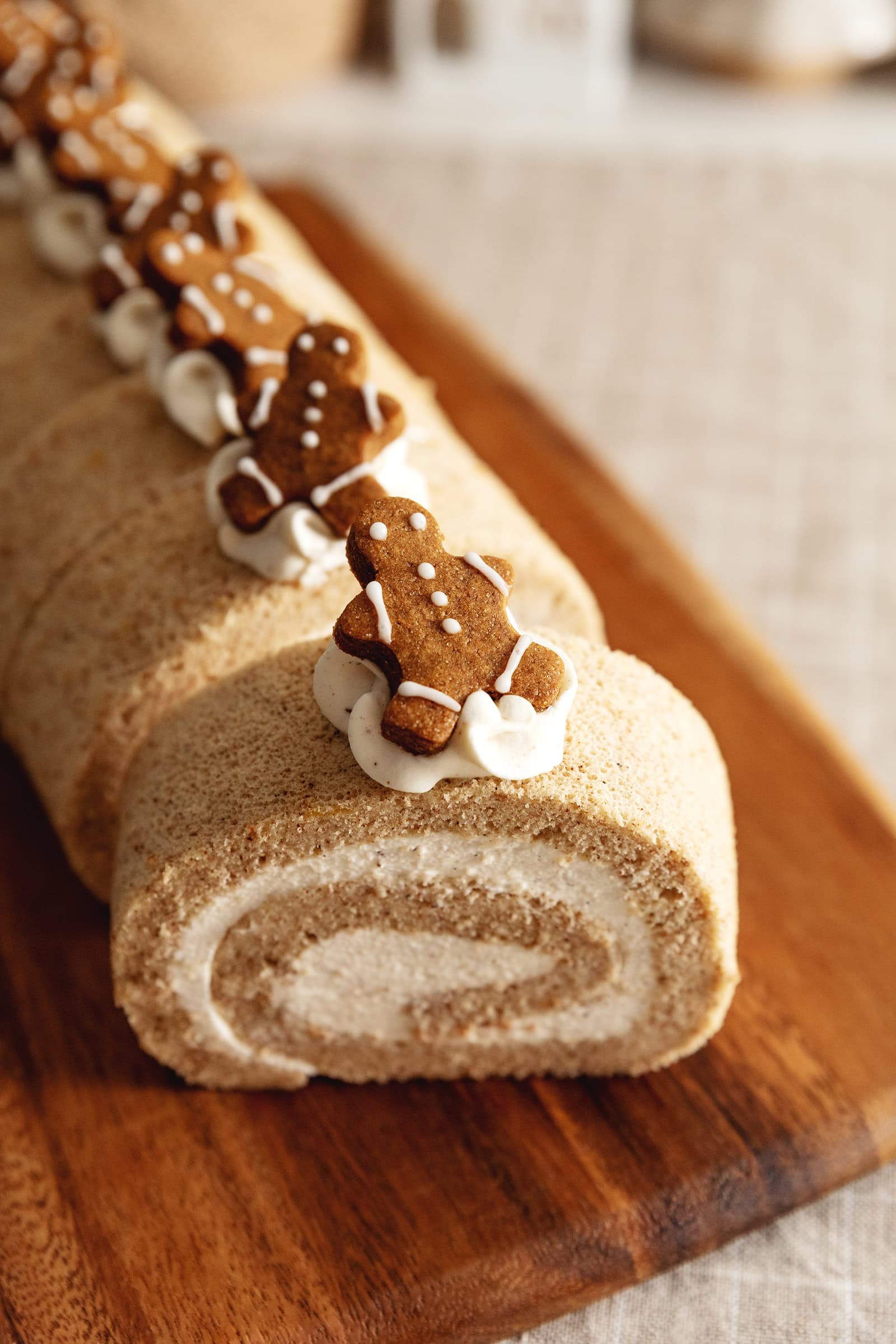 Close up of a gingerbread man cookie on top of a slice of gingerbread roll cake.