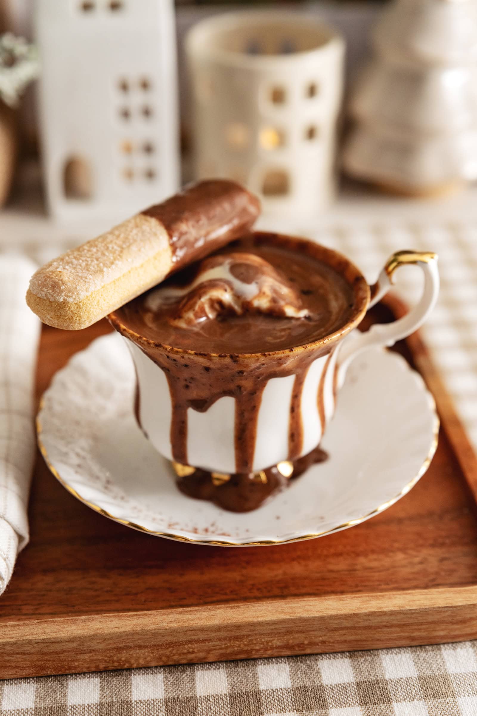 A teacup of tiramisu hot chocolate with hot chocolate running down the sides of the cup.