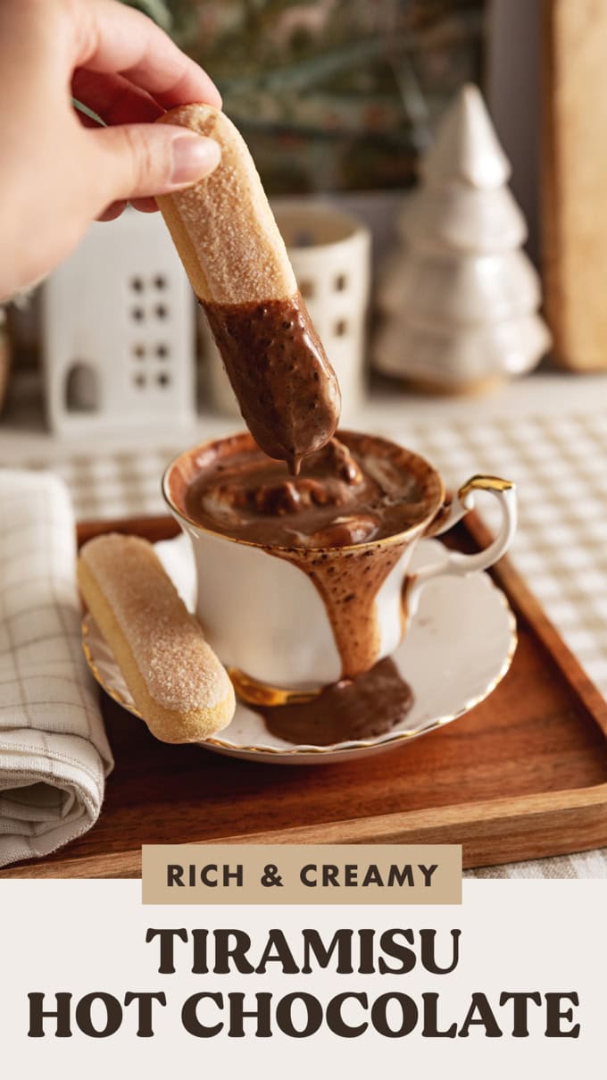 Hand dipping a ladyfinger into a teacup of tiramisu hot chocolate.