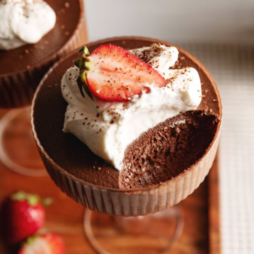 A chocolate mousse cup with a spoonful scooped out of the cup to show the texture inside.